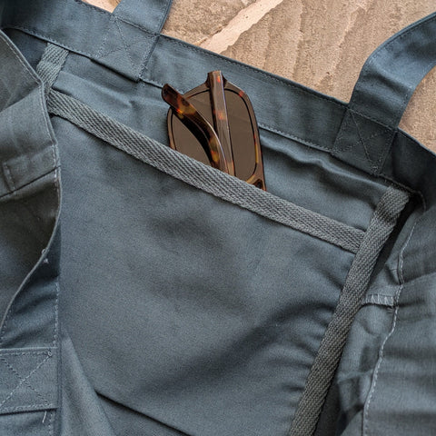 Close up of teal cotton tote with sunglasses peaking out of an inside pocket