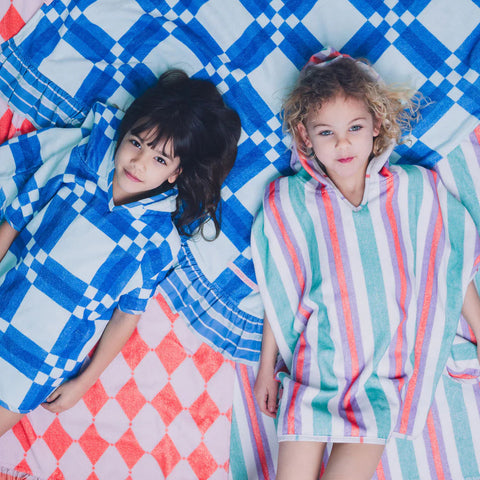 Two children lying on colorful patterned towels