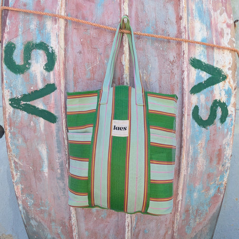 Striped green bag hanging on a rusted metal boat.