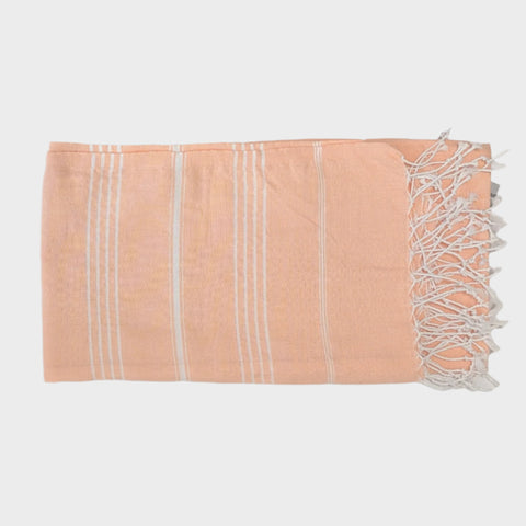 Peach-colored towel with white stripes and fringes on a light gray background