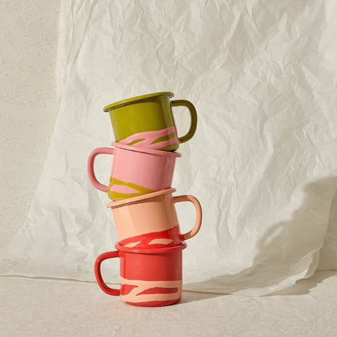 Stack of colorful enamel mugs on a textured white background