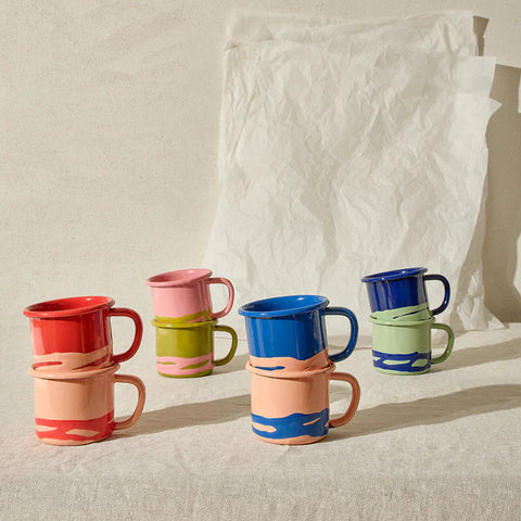 Set of colorful mugs stacked on a neutral background