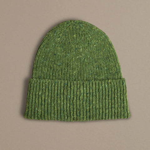 Green knit beanie on a beige background