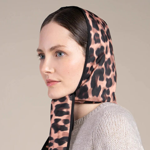 Woman wearing a leopard print headscarf against a beige background