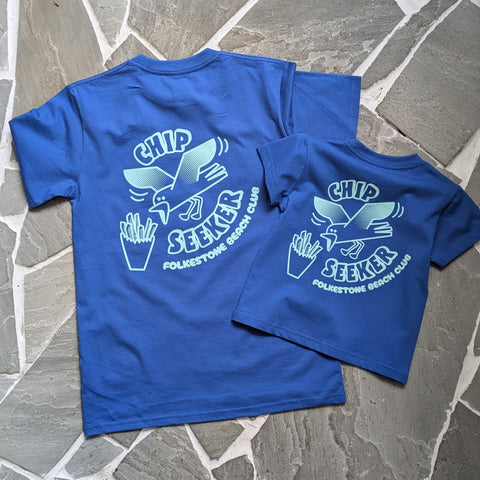 Two blue t-shirts with a logo on a stone surface