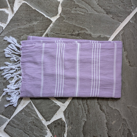 Purple towel with white stripes on a stone floor background