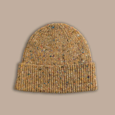 A yellow knitted beanie with colourful flecks against a beige background