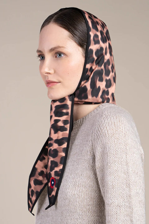 Woman wearing a leopard print headscarf against a beige background