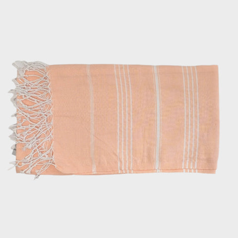 Peach-colored towel with white stripes and fringes on a light gray background