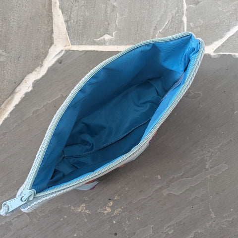An open pouch showing a blue lining sat on a stone floor 