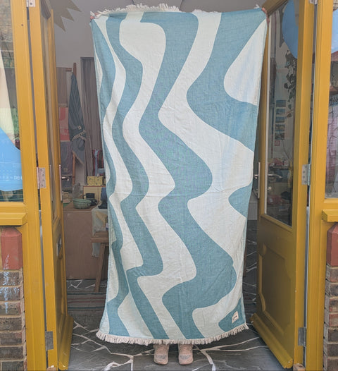 Person holding a blue and white patterned blanket in front of a store window.