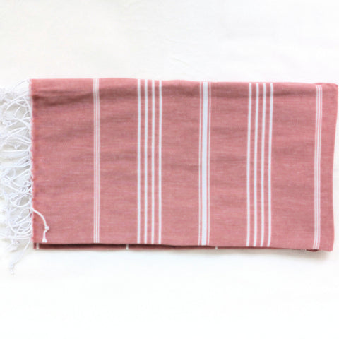 brick red towel with white stripes and white tassels on a white background