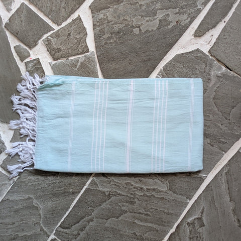 Light blue towel with white fringes on a stone surface