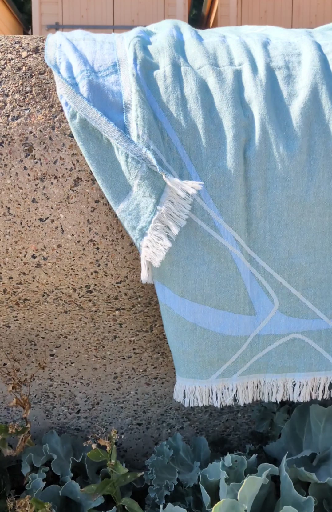 Laes Pool Turkish Towel - Beach Towel -  blue and sage - hanging over a stone wall at the beach - shop now